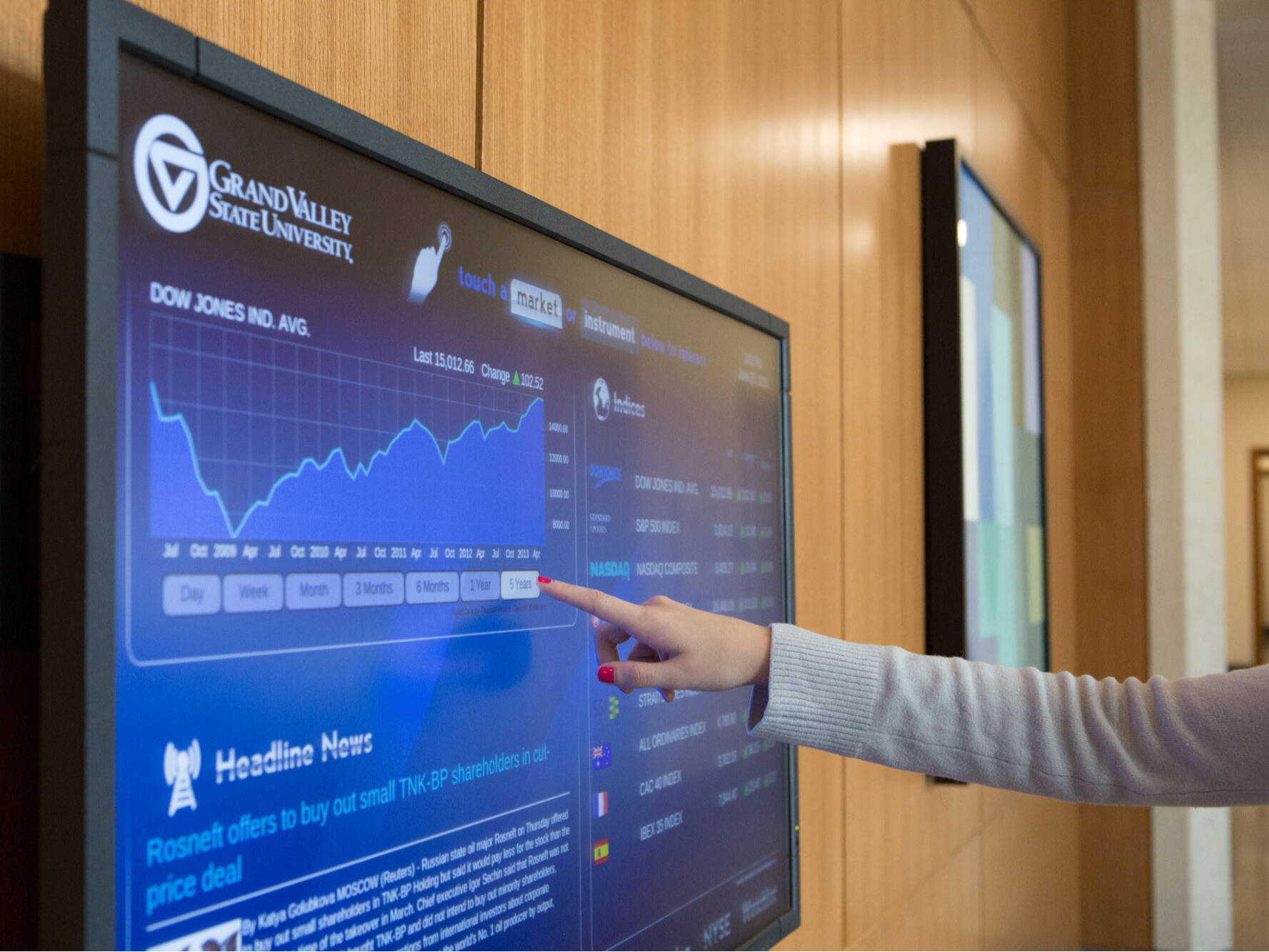 Hand pointing at a screen showing the DOW Jones Ind. chart